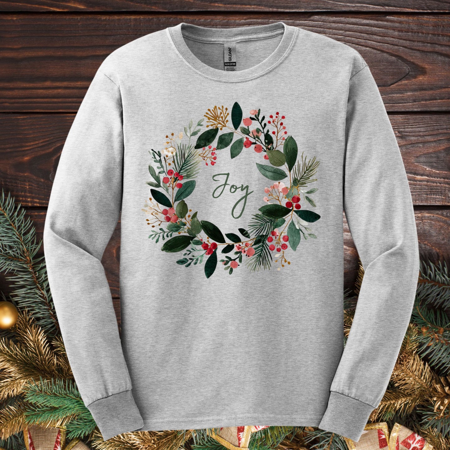 Ash gray Gildan long sleeve tee with a watercolor Christmas wreath and "Joy" in the center.