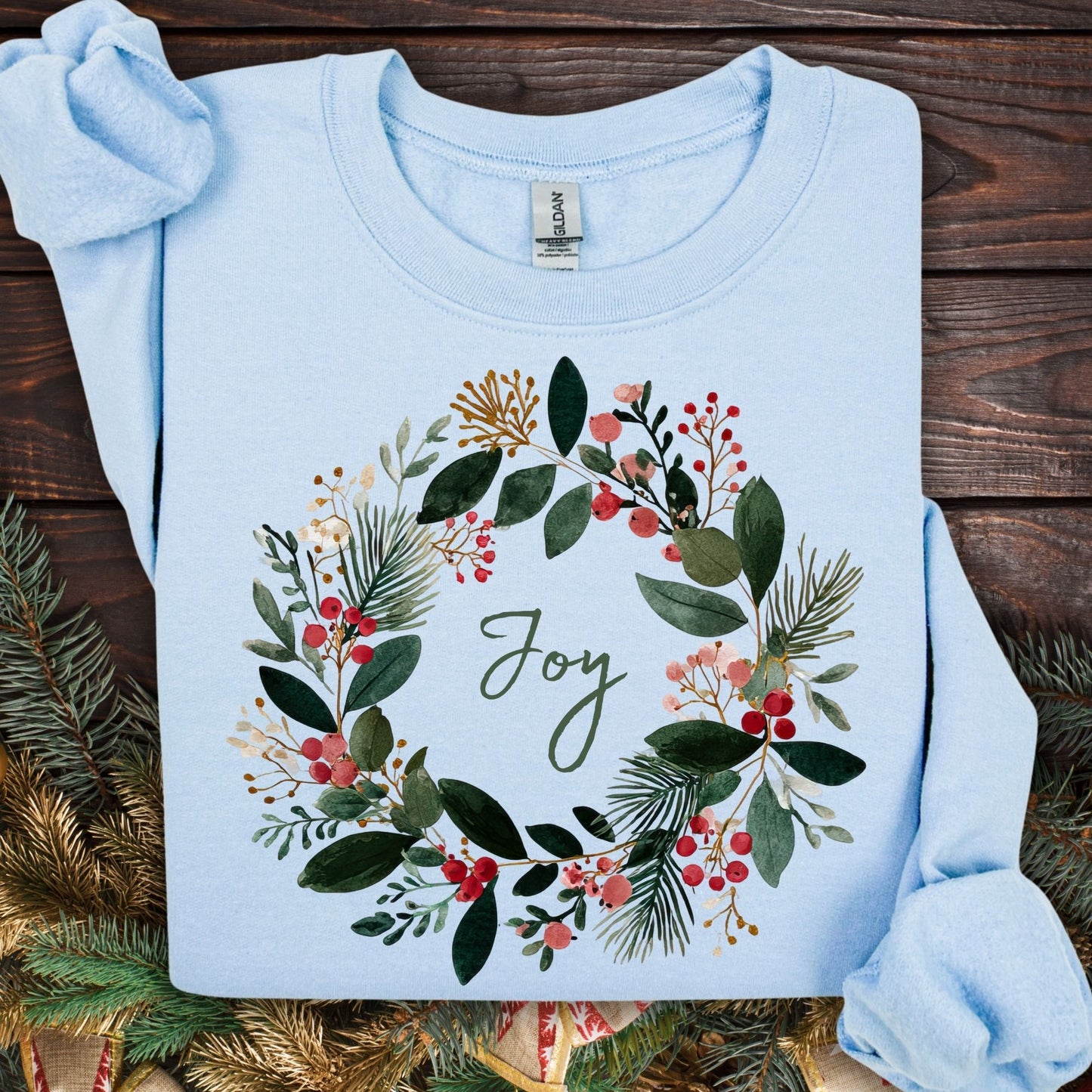 Light blue Gildan crewneck sweatshirt with a watercolor Christmas wreath and "Joy" in the center.