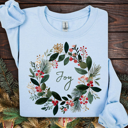 Light blue Gildan crewneck sweatshirt with a watercolor Christmas wreath and "Joy" in the center.