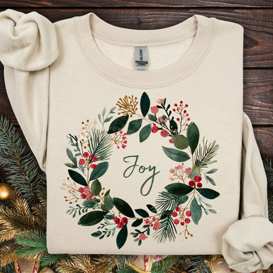Sand Gildan crewneck sweatshirt with a watercolor Christmas wreath and "Joy" in the center.