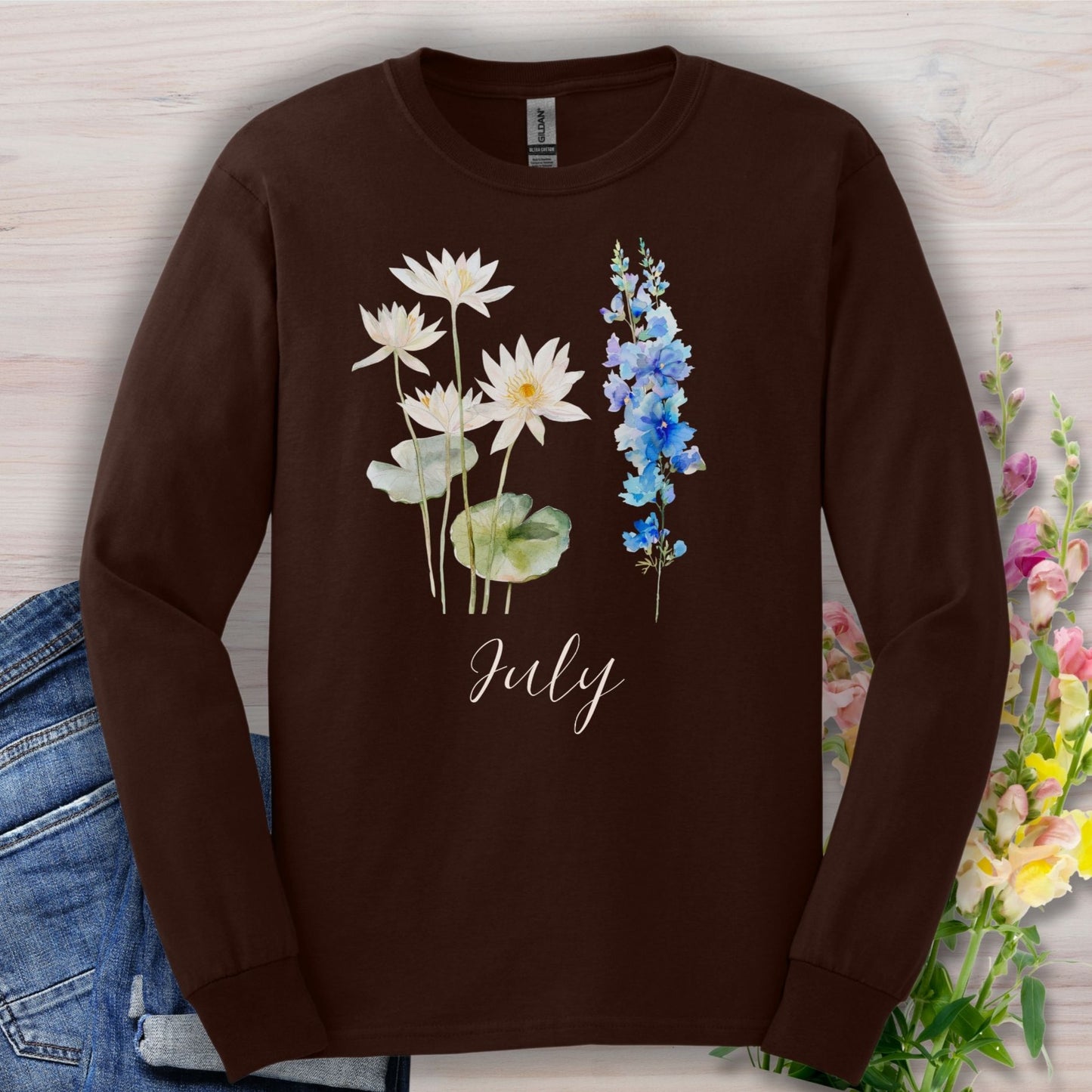 Dark chocolate long-sleeve tee with watercolor waterlily and larkspur flowers and "July" text.