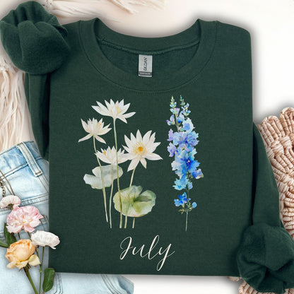Forest Green unisex sweatshirt with watercolor waterlilies, larkspur, and "July" text.