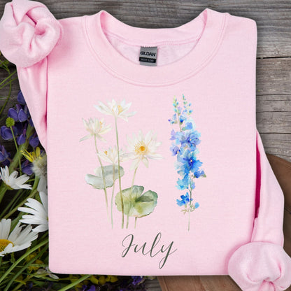 Light pink July birth month flower sweatshirt with watercolor waterlilies and blue larkspur.