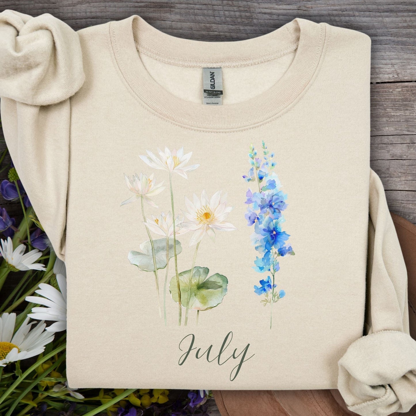 Sand unisex sweatshirt with watercolor waterlilies, blue larkspur, and "July" text.