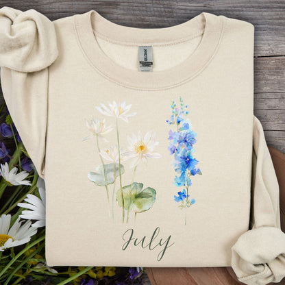 Sand unisex sweatshirt with watercolor waterlilies, blue larkspur, and "July" text.