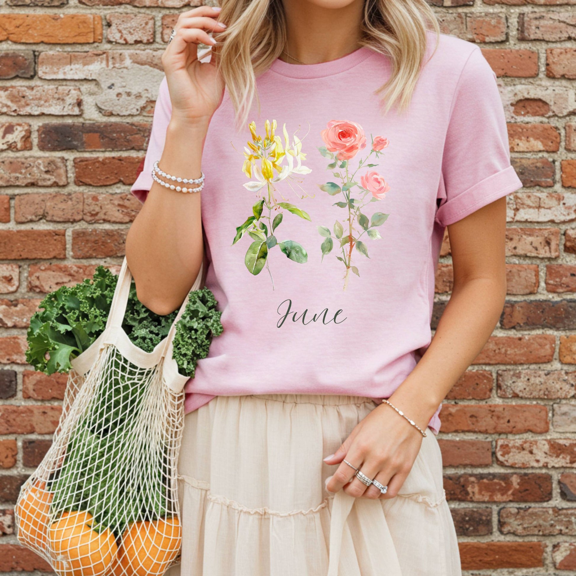 Garment-dyed pink cotton t-shirt with watercolor honeysuckle, rose, and "June" text.