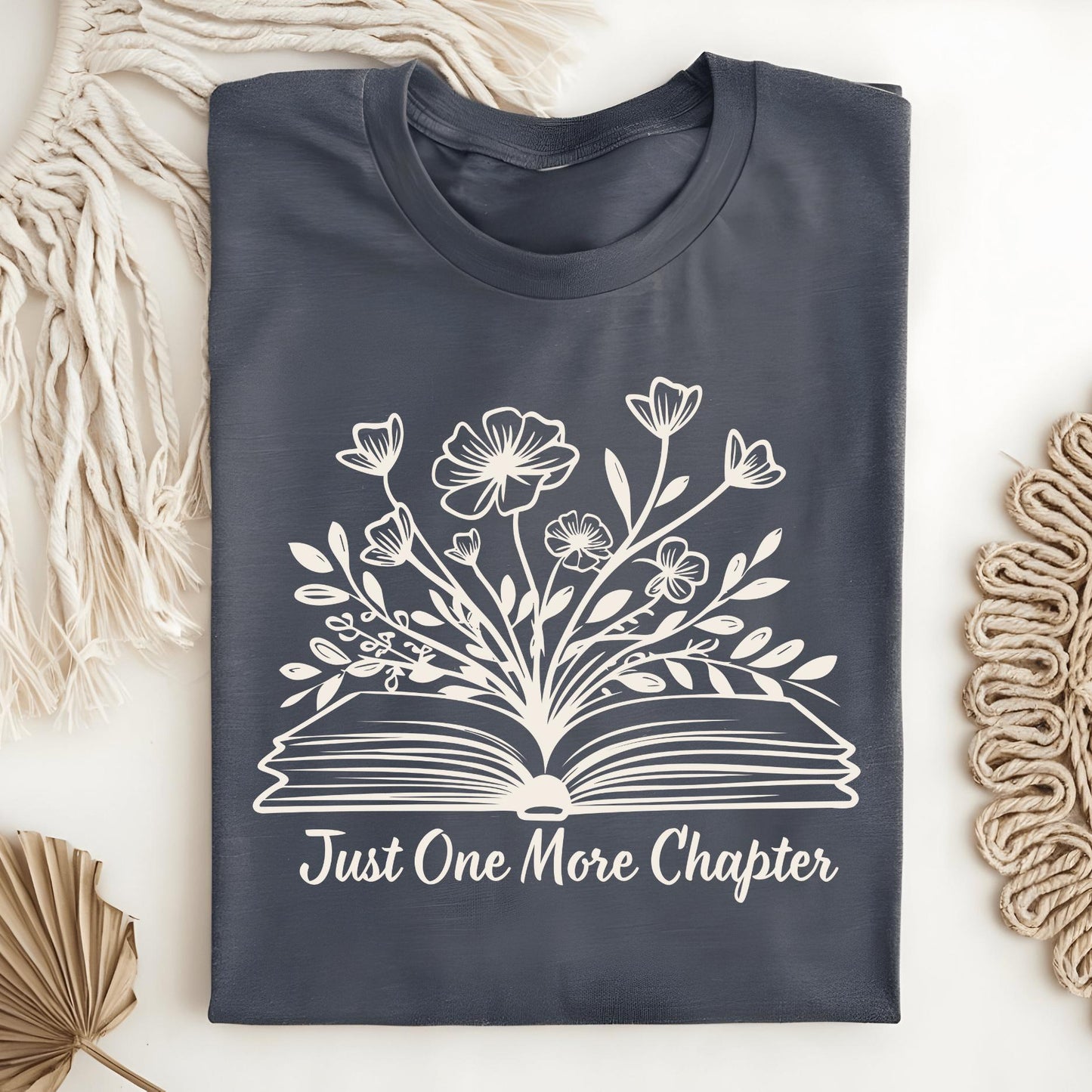Dark Heather tee with "Just One More Chapter" text and wildflowers blooming from an open book.