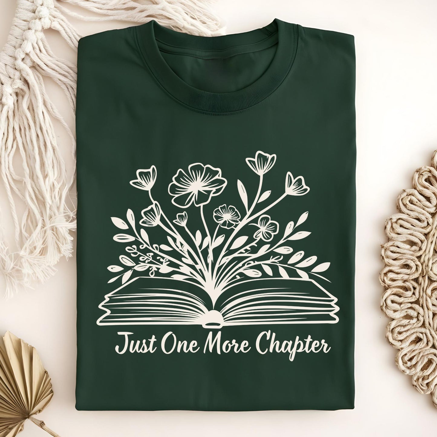 Forest Green "Just One More Chapter" t-shirt with white outline of wildflowers blooming from an open book.