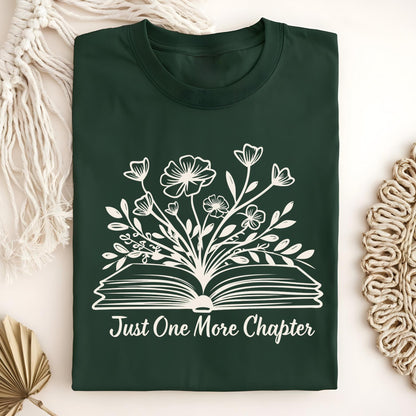 Forest Green "Just One More Chapter" t-shirt with white outline of wildflowers blooming from an open book.