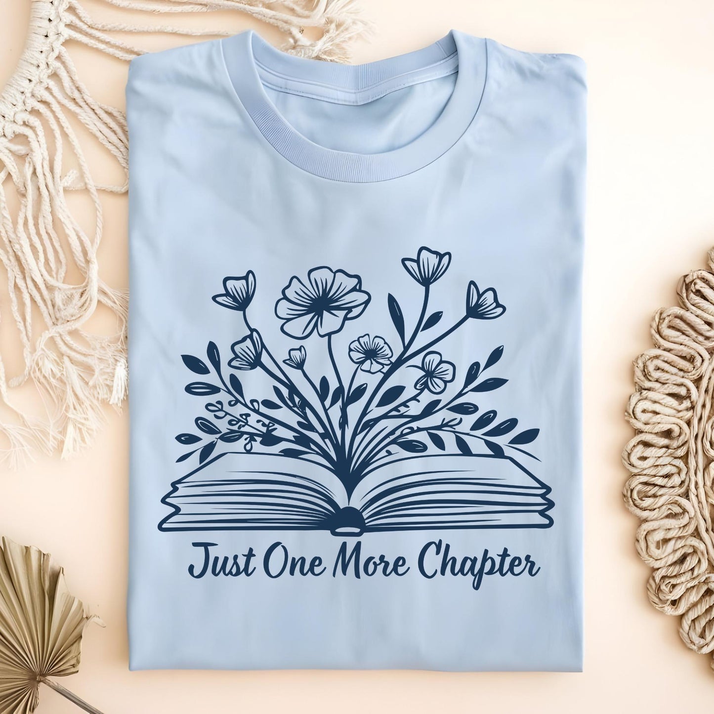 Light blue "Just One More Chapter" t-shirt with a vintage book and wildflowers design.