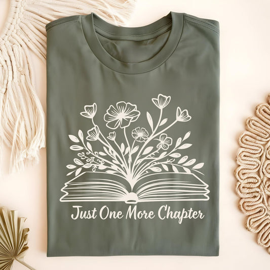 Military Green "Just One More Chapter" t-shirt with white wildflowers blooming from an open book.