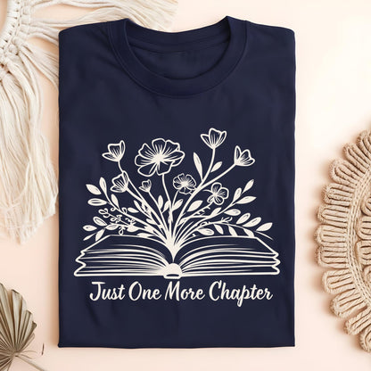 Navy "Just One More Chapter" tee with white outline of wildflowers blooming from an open book.