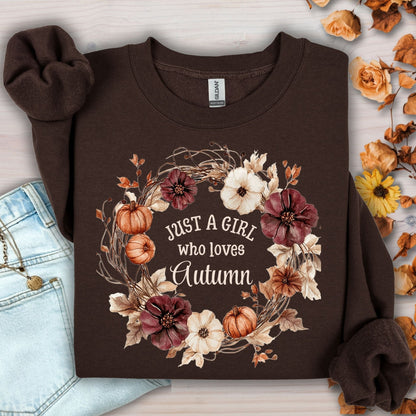 Dark chocolate Gildan sweatshirt with "Just a Girl who loves Autumn" text in a watercolor floral and pumpkin wreath.