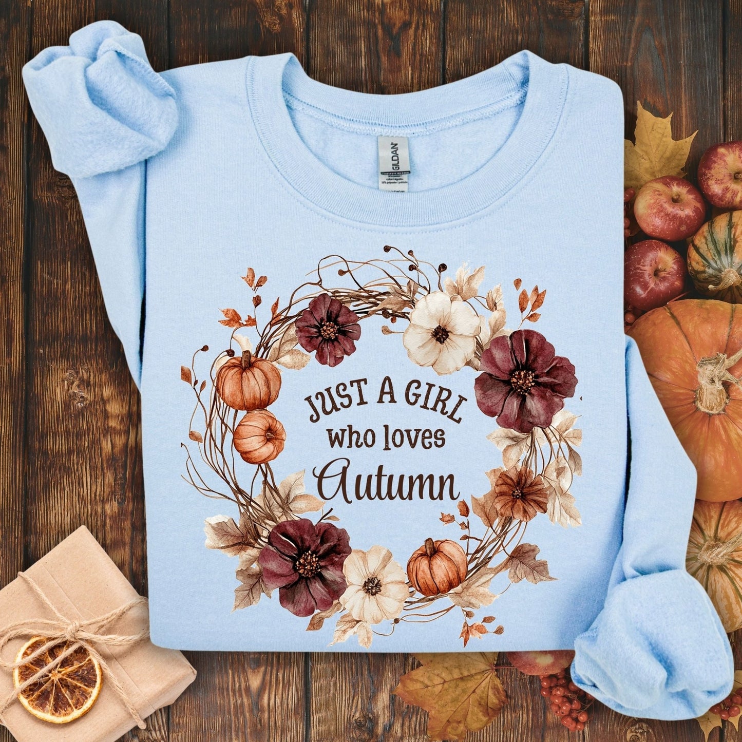 Light blue cotton-blend sweatshirt with "Just a Girl who loves Autumn" text and watercolor fall wreath design.