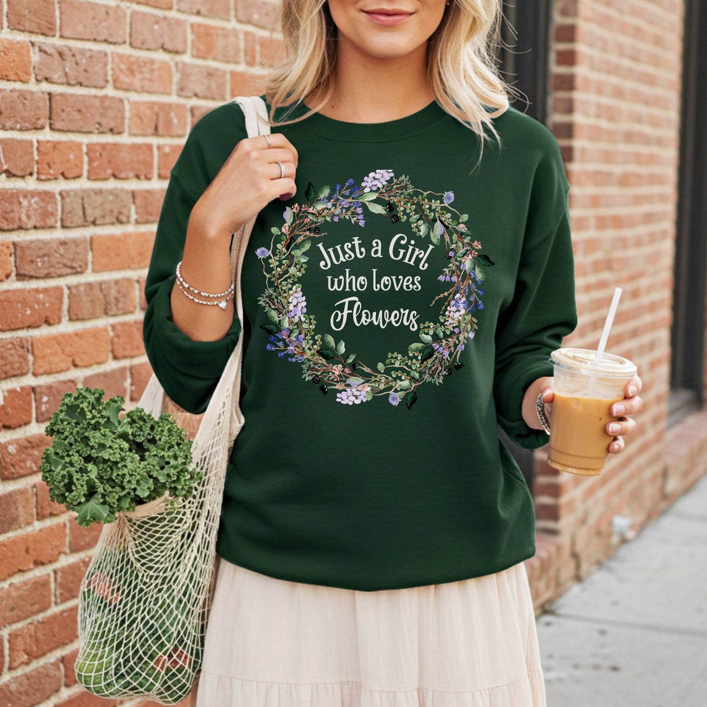 Woman in a dark green crewneck sweatshirt with a floral wreath and "Just a Girl who loves Flowers" text.