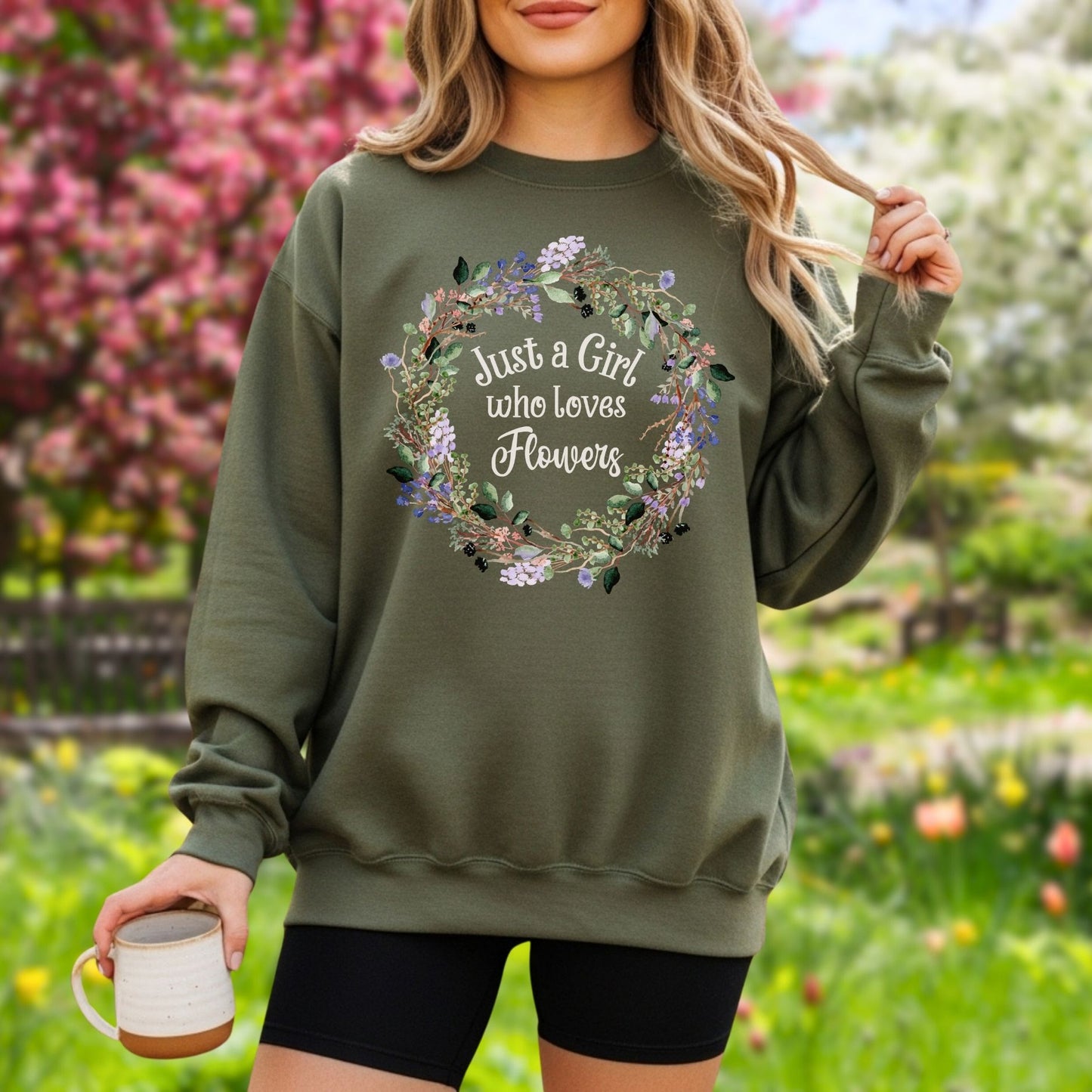 Woman in an olive green crewneck sweatshirt with a "Just a Girl who loves Flowers" wreath design.