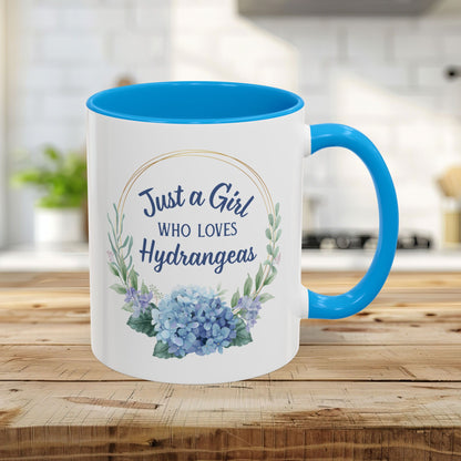 White ceramic 11oz mug with light blue interior and handle, featuring a watercolor hydrangea wreath and "Just a Girl Who Loves Hydrangeas" text.
