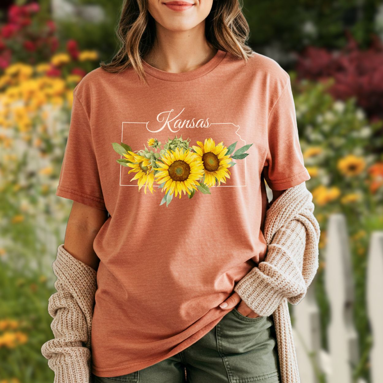 Garment-dyed terracotta t-shirt with a Kansas outline, "Kansas" text, and vibrant yellow sunflowers.
