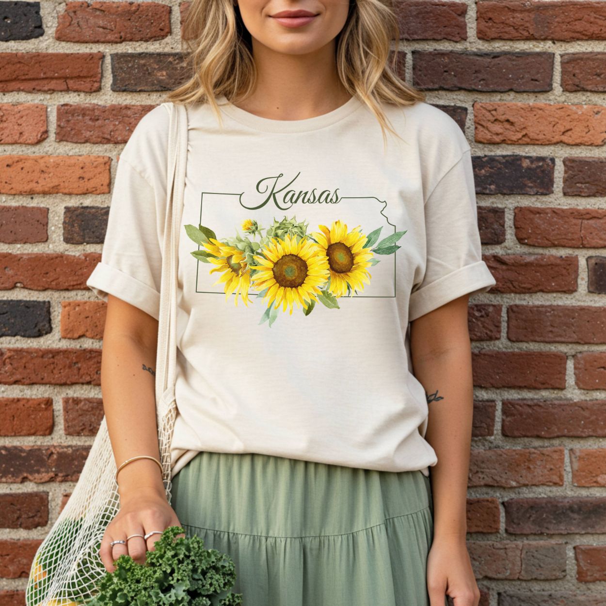 Garment-dyed cream t-shirt with a Kansas state outline and golden sunflower graphic.