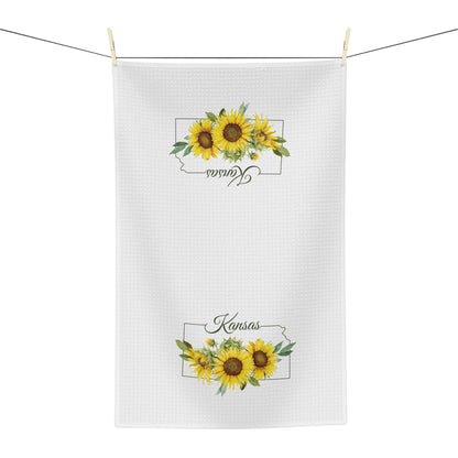 White microfiber tea towel with "Kansas" and golden sunflowers, hanging on a line.