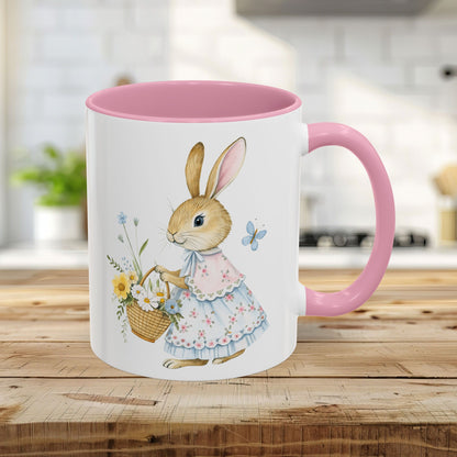 White 11oz mug with a pink interior/handle, featuring a watercolor bunny in a floral dress holding a flower basket.