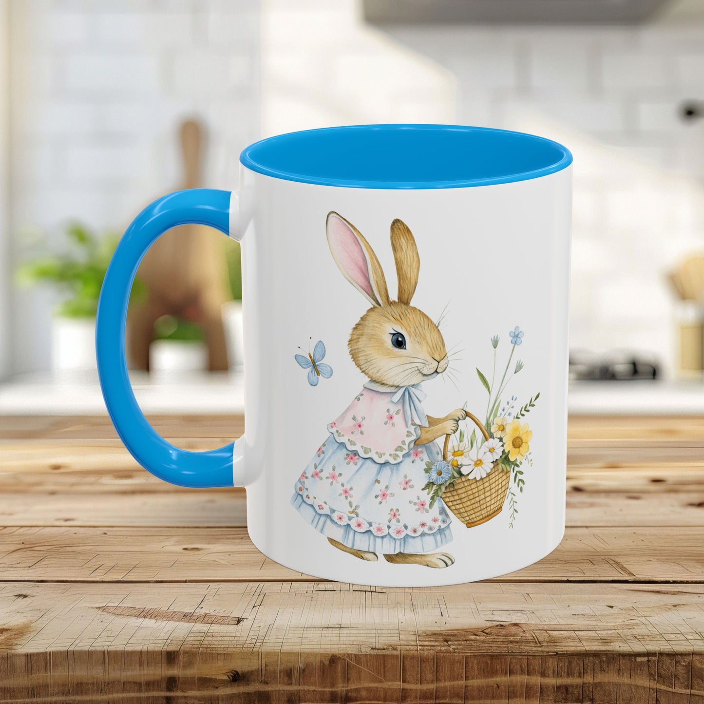 White ceramic mug with a blue handle and interior, featuring a watercolor bunny in a dress holding a flower basket.