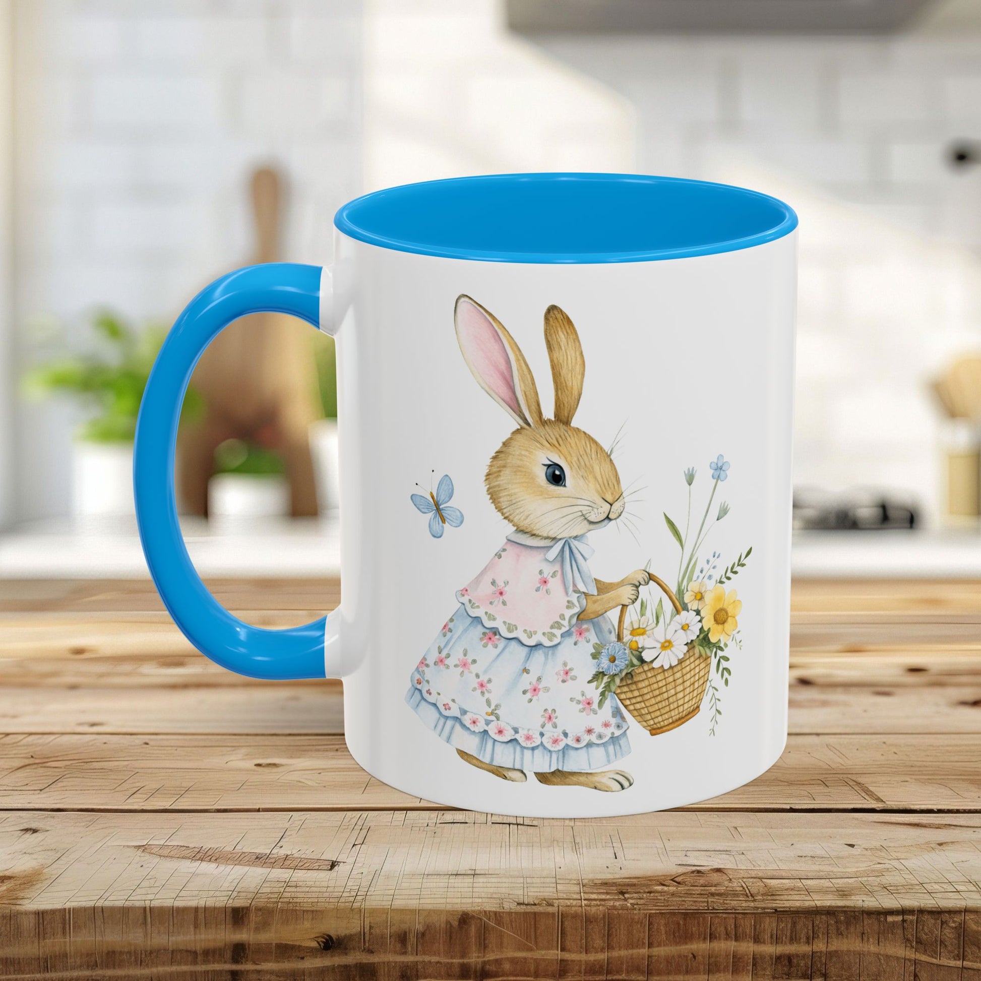 White ceramic mug with a blue handle and interior, featuring a watercolor bunny in a dress holding a flower basket.