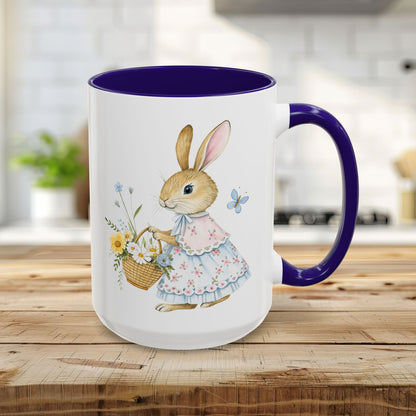 15oz white ceramic mug with a blue interior/handle, featuring a watercolor bunny in a floral dress holding a flower basket.