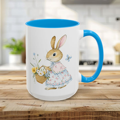 15oz white mug with a blue handle and interior, featuring a watercolor bunny in a dress holding a flower basket.
