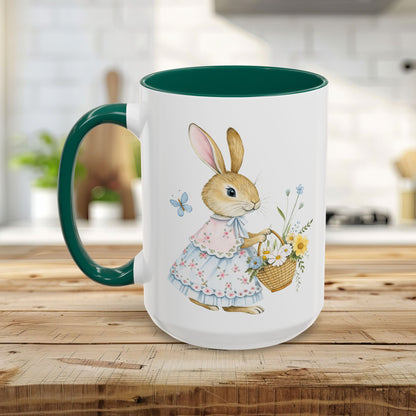 White ceramic mug with a green handle and interior, featuring a watercolor bunny in a dress holding a flower basket.