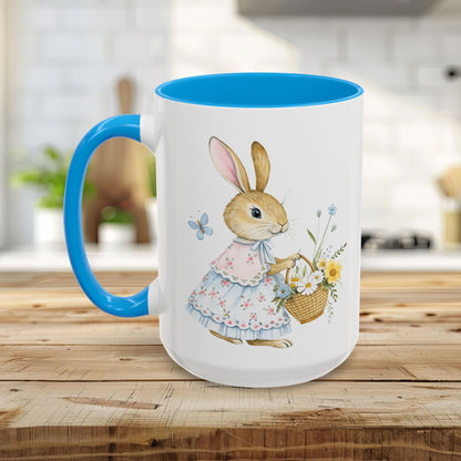 White ceramic mug with blue interior and handle, featuring a watercolor bunny in a floral dress holding a flower basket.