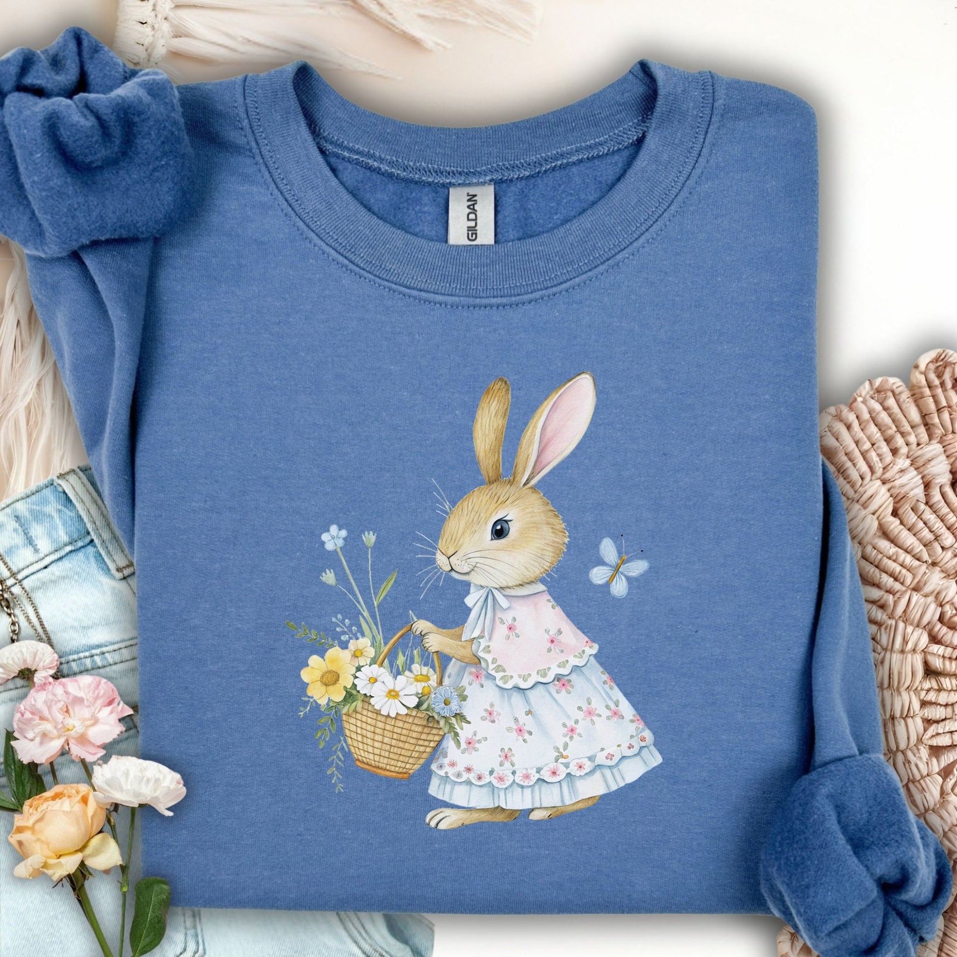 Indigo blue sweatshirt with a whimsical bunny in a floral dress holding a flower basket.