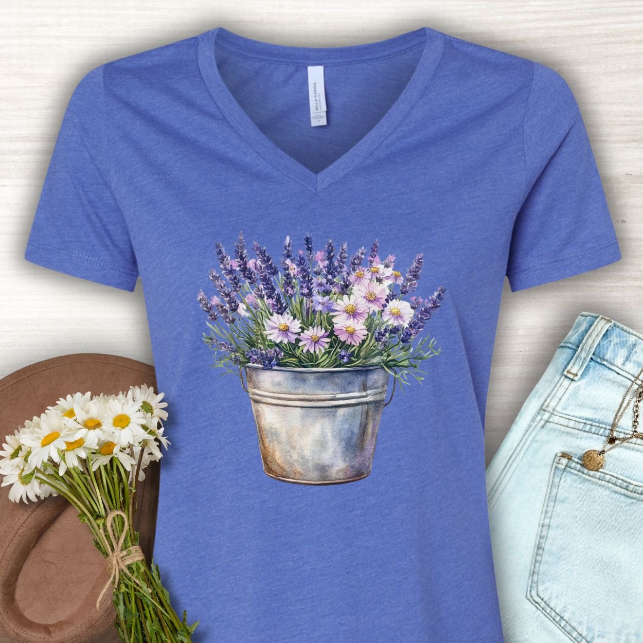Heather True Royal v-neck tee with a faded botanical print of lavender and daisies in a rustic metal pot.