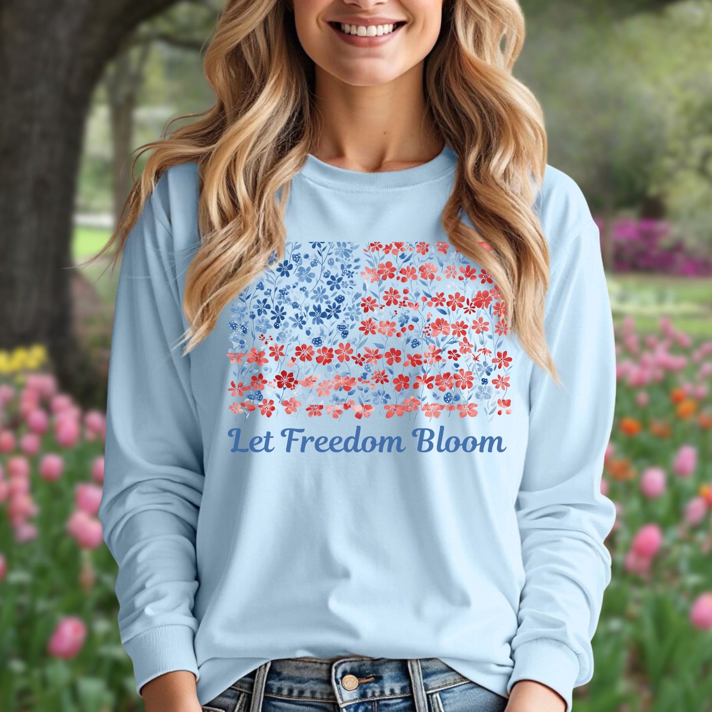Woman in a light blue long sleeve tee with a faded red and blue floral flag graphic and "Let Freedom Bloom" text.