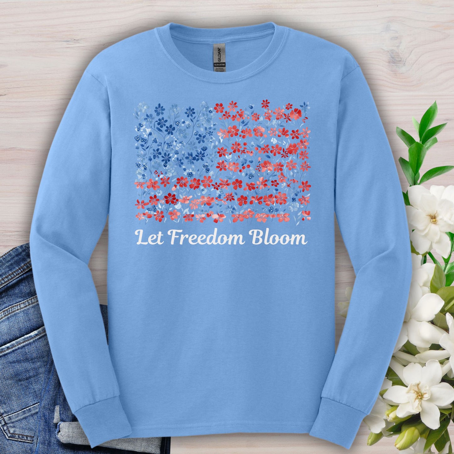 Carolina Blue long sleeve tee with a faded floral American flag graphic and "Let Freedom Bloom" text.