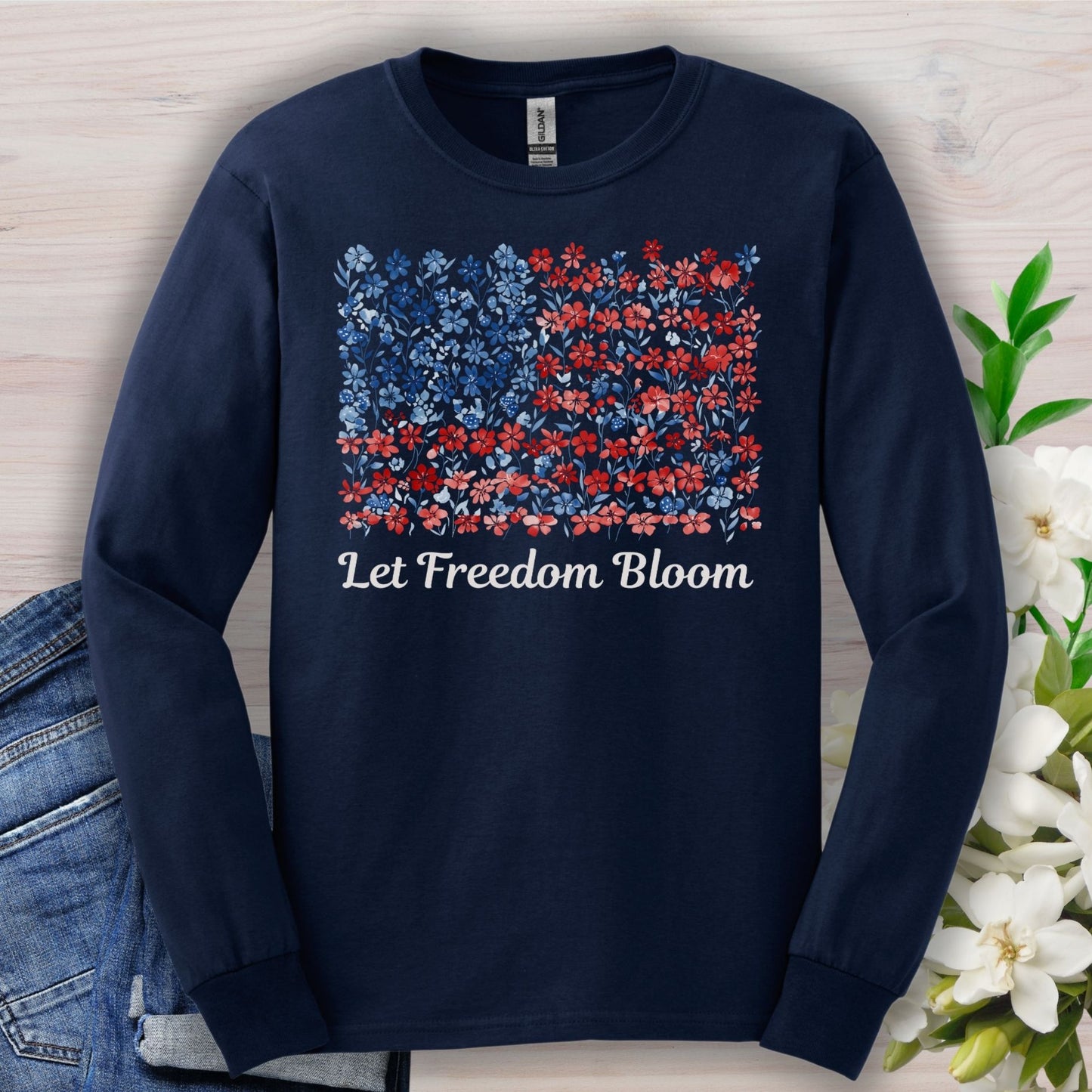Navy long sleeve tee with a faded floral flag graphic and "Let Freedom Bloom" text.