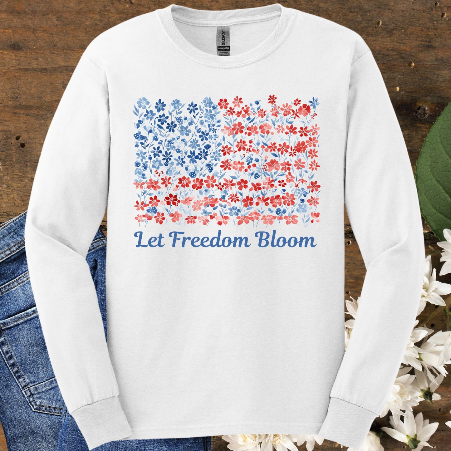 White long sleeve tee with a faded red and blue floral flag graphic and "Let Freedom Bloom" text.
