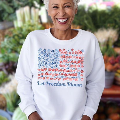 Smiling woman in white crewneck sweatshirt with a floral flag design and "Let Freedom Bloom" text.