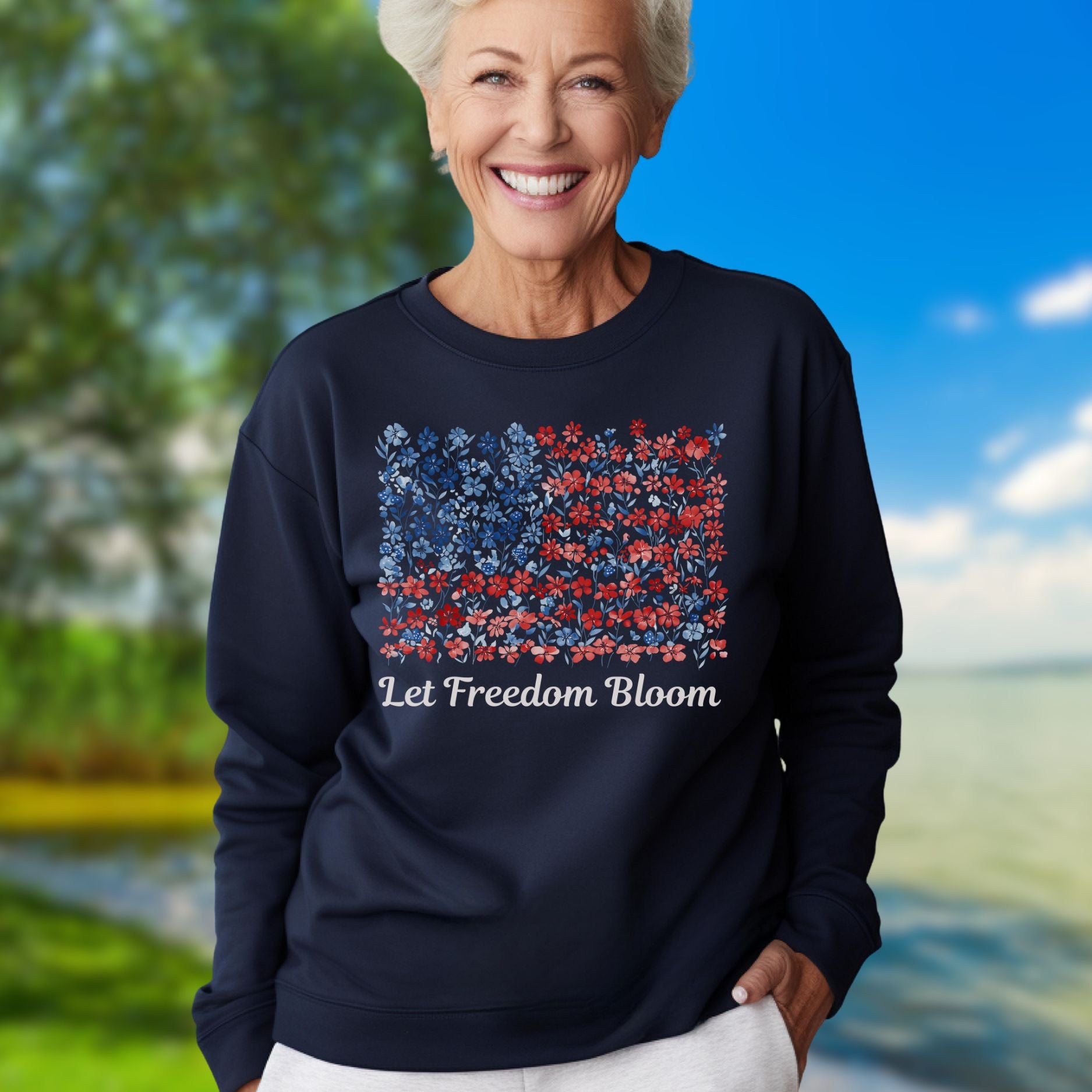 Woman in navy "Let Freedom Bloom" floral flag sweatshirt, smiling outdoors.