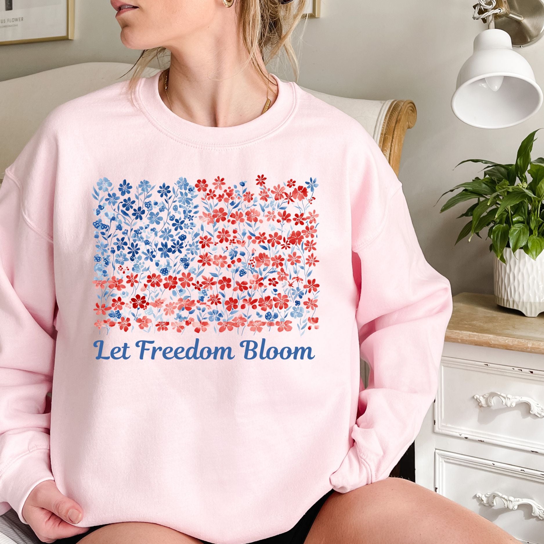 Pink cotton-poly sweatshirt with a floral American flag design and "Let Freedom Bloom" in blue script.