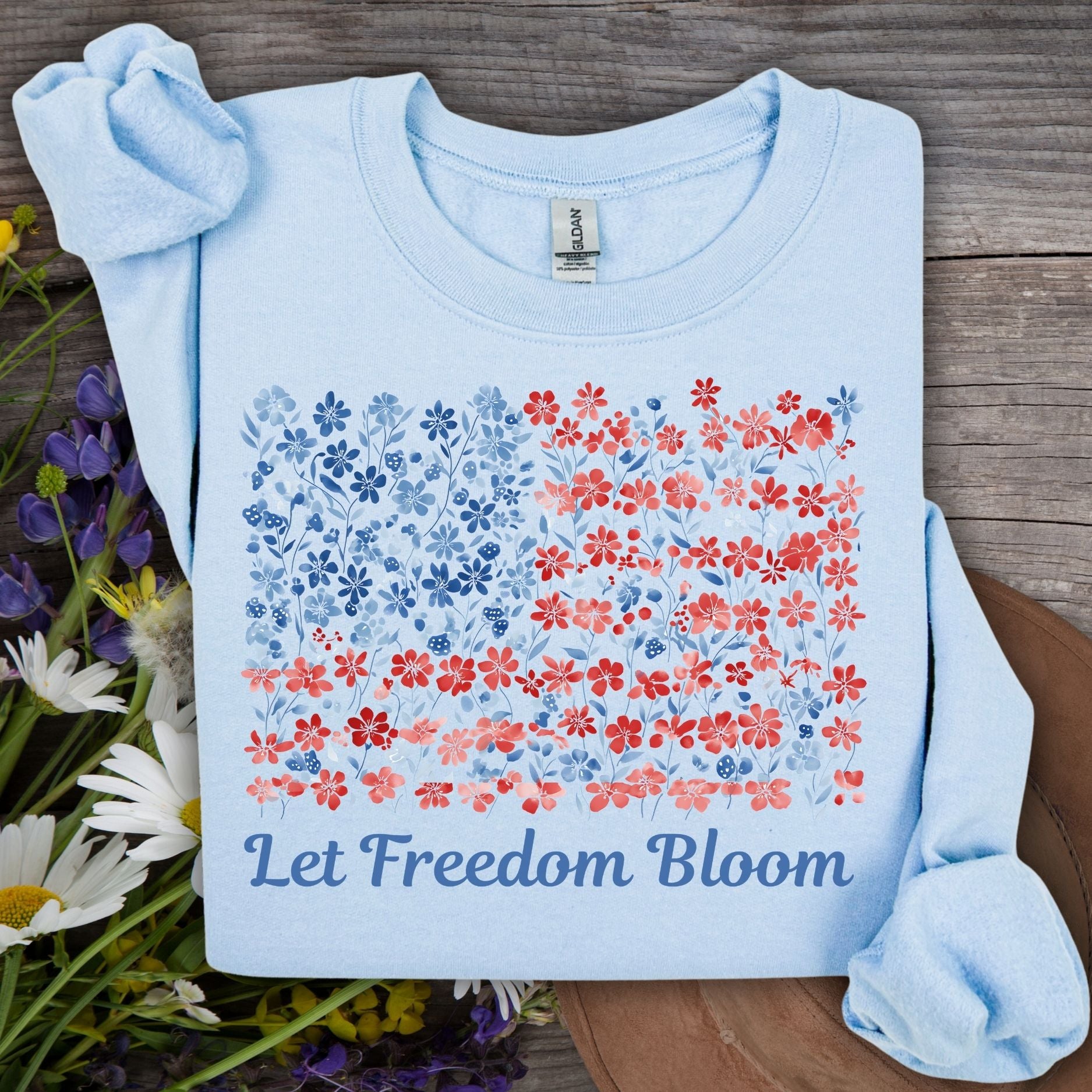 Light blue crewneck sweatshirt with a floral flag design and "Let Freedom Bloom" text.