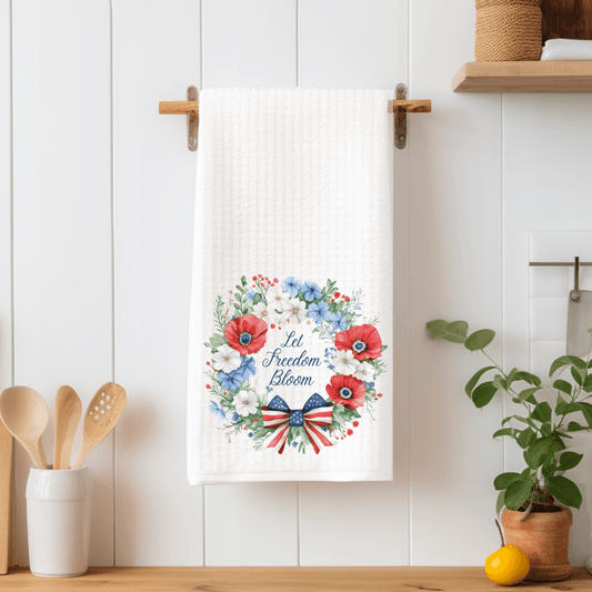 White microfiber tea towel with "Let Freedom Bloom" in a red, white, and blue floral wreath and bow.