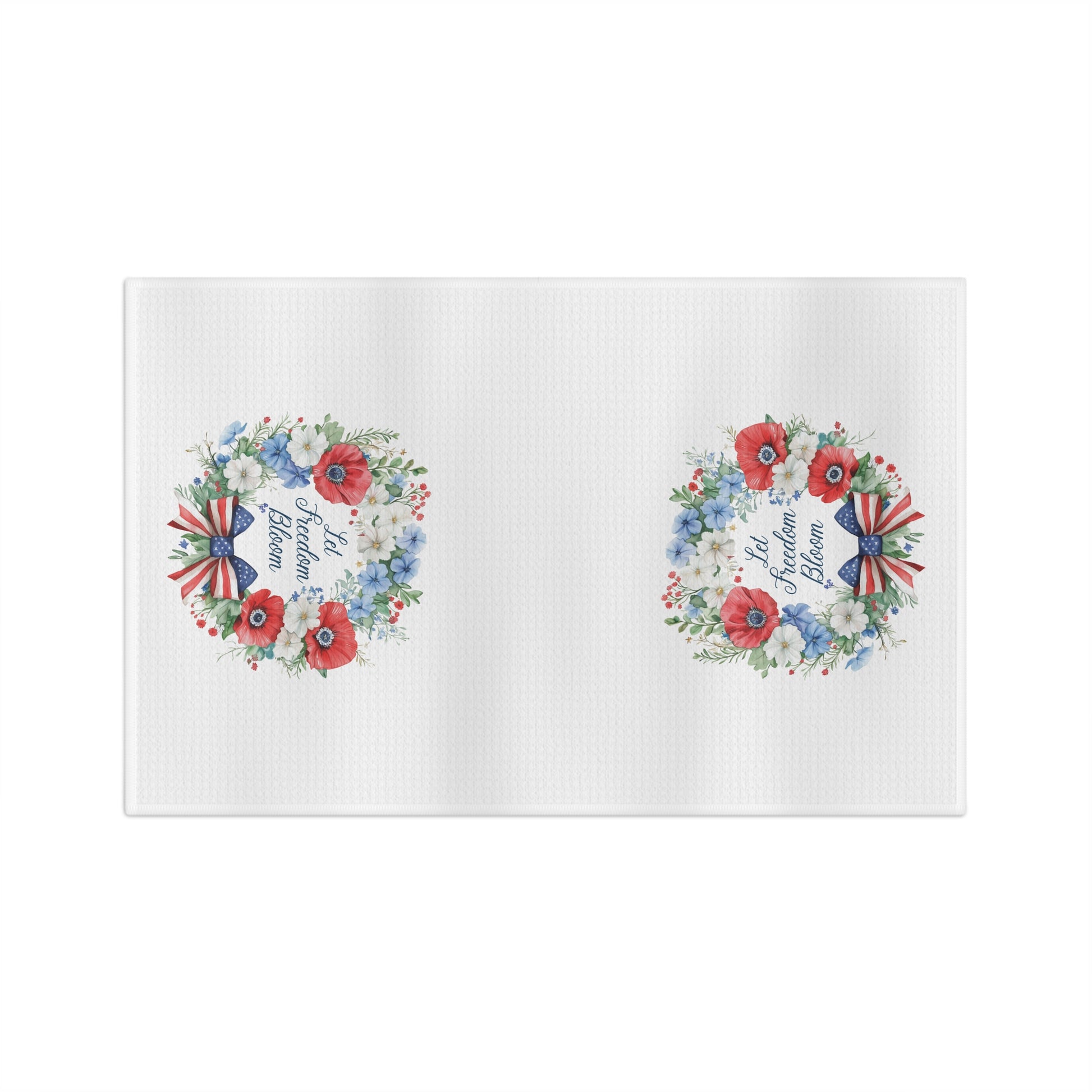 White microfiber tea towel with two watercolor wreaths of red, white, and blue florals and "Let Freedom Bloom.