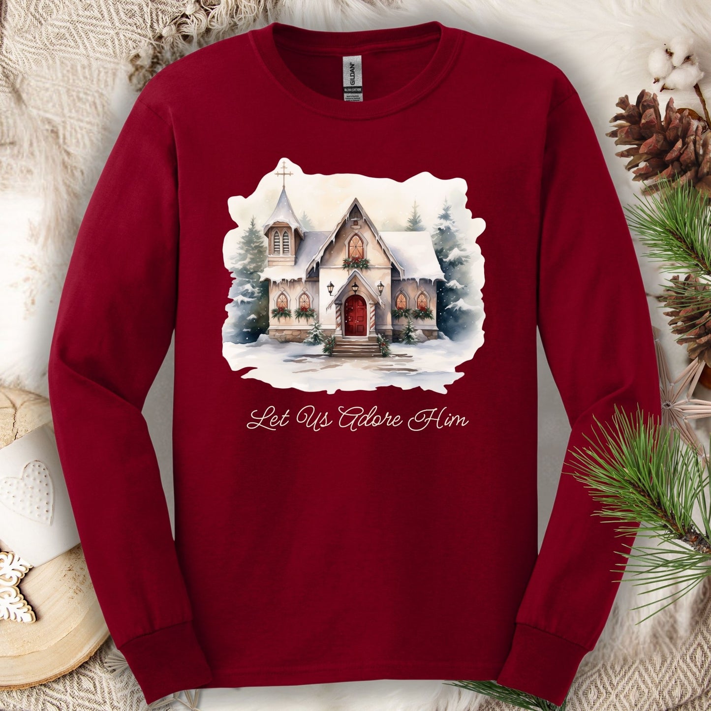 Cardinal Red long sleeve tee with a watercolor snow-covered country chapel and "Let Us Adore Him" text.