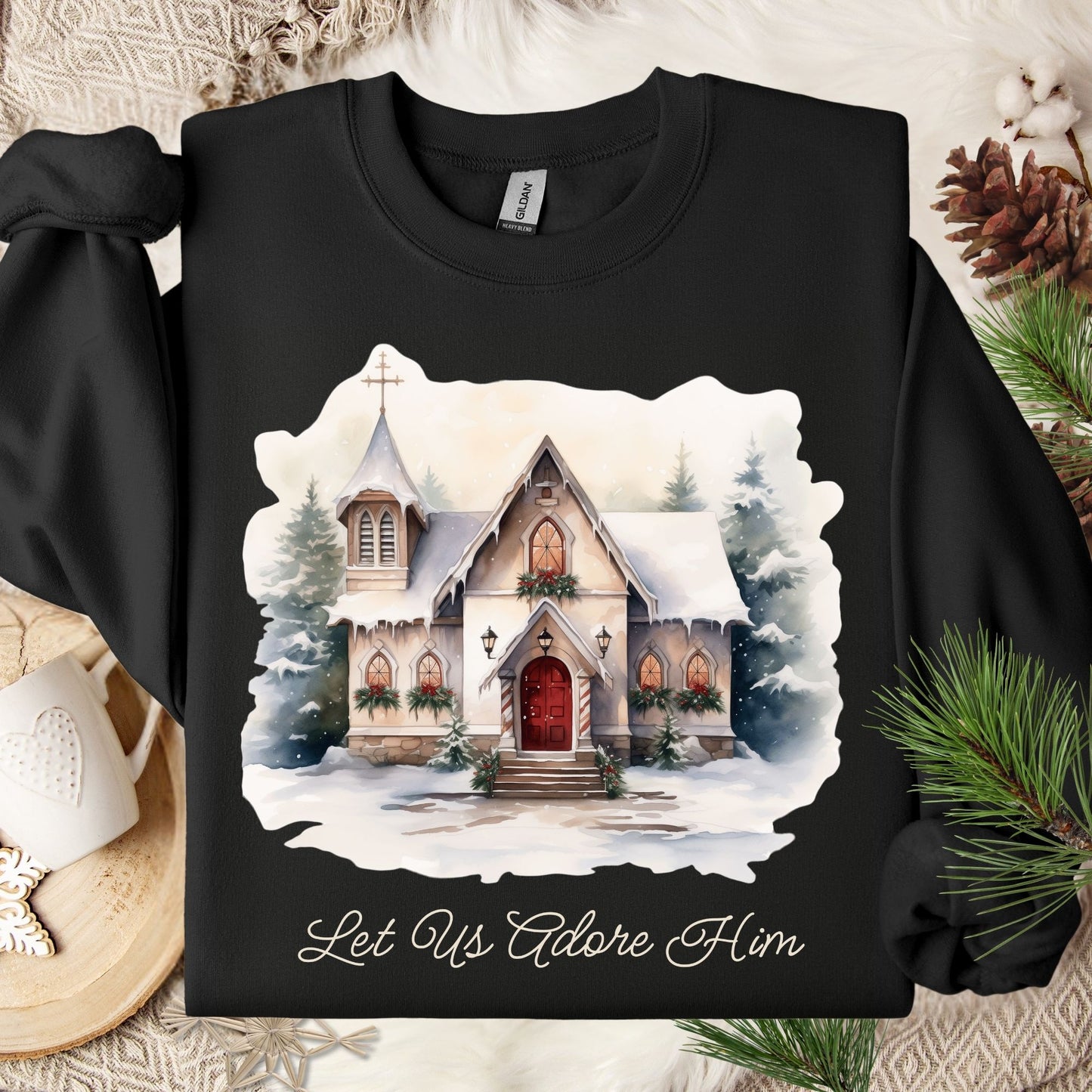 Black Gildan sweatshirt with a snowy country chapel design and "Let Us Adore Him" text.
