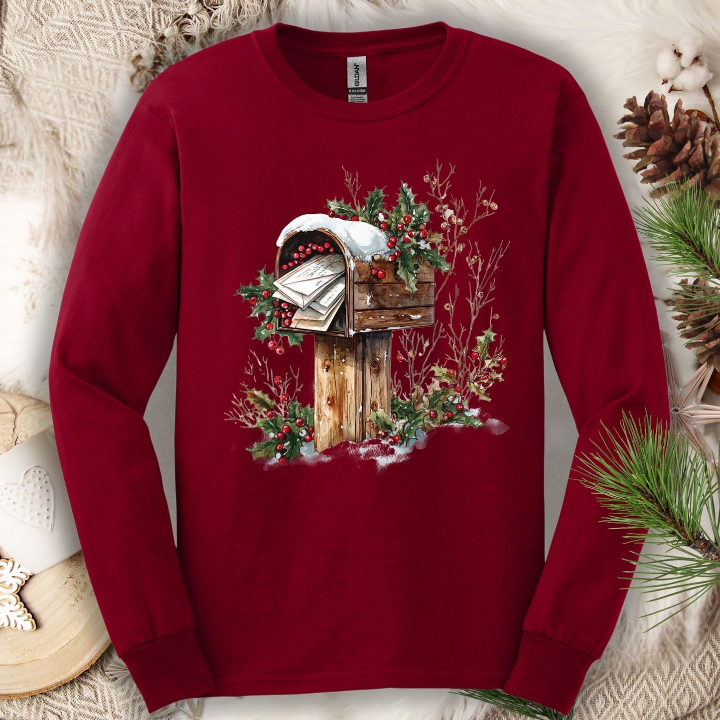 Cardinal Red long sleeve tee with a watercolor wooden mailbox, snow, and holly berries.