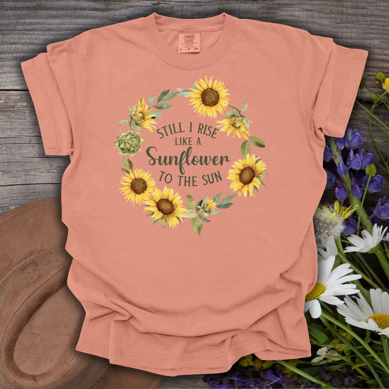 Terracotta S-size t-shirt with a sunflower wreath and "Still I Rise Like a Sunflower to the Sun" text.