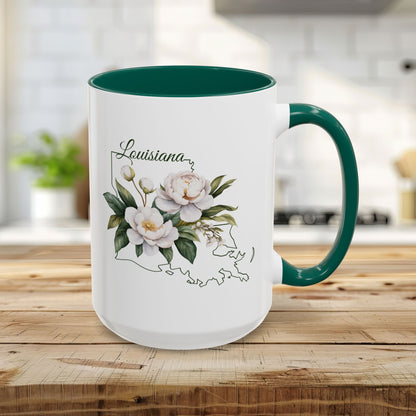 White 15oz ceramic mug with green interior and handle, featuring a watercolor magnolia bouquet over a Louisiana state outline.