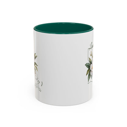 White ceramic mug with green interior and handle, featuring a watercolor magnolia bouquet and Louisiana state outline.