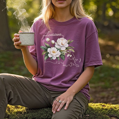 Garment-dyed plum t-shirt with a white magnolia illustration over a subtle Louisiana outline.